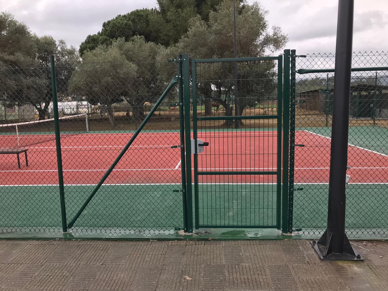 Una cancha de tenis con una puerta verde que conduce a ella.