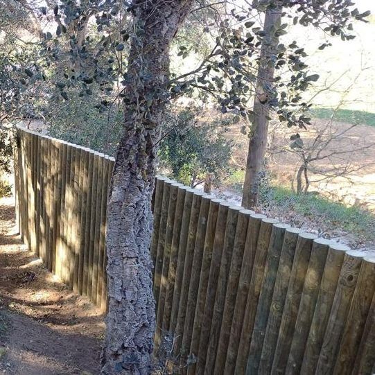 Una valla de madera está rodeada de árboles en un bosque.