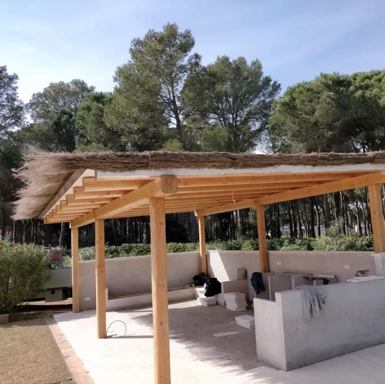 Una estructura de madera con techo de paja rodeada de árboles.