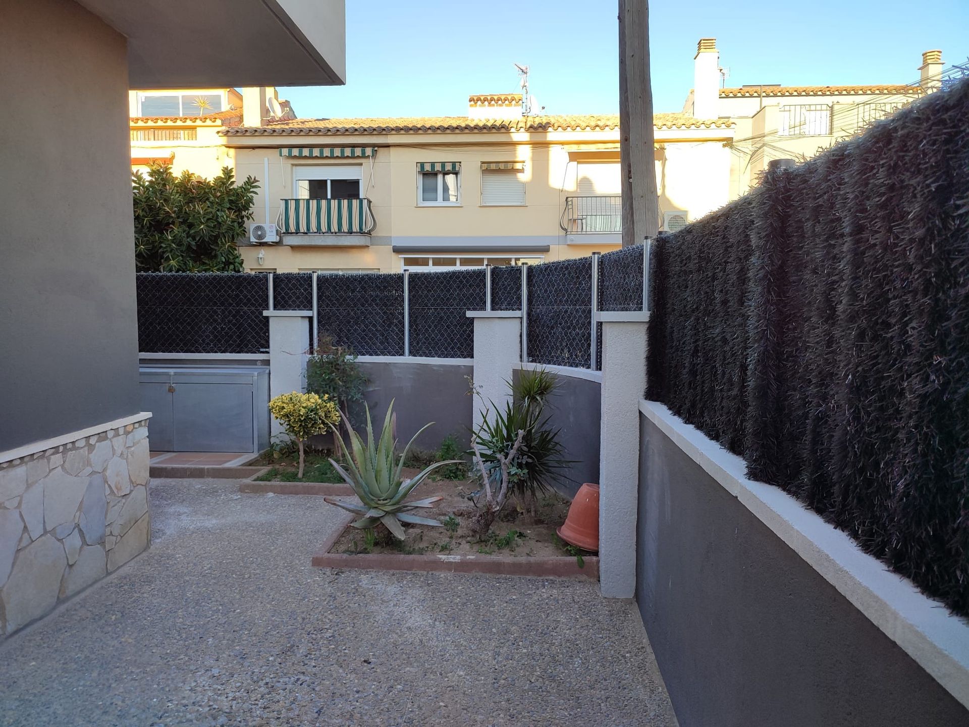 Una valla con algunas plantas delante de un edificio.