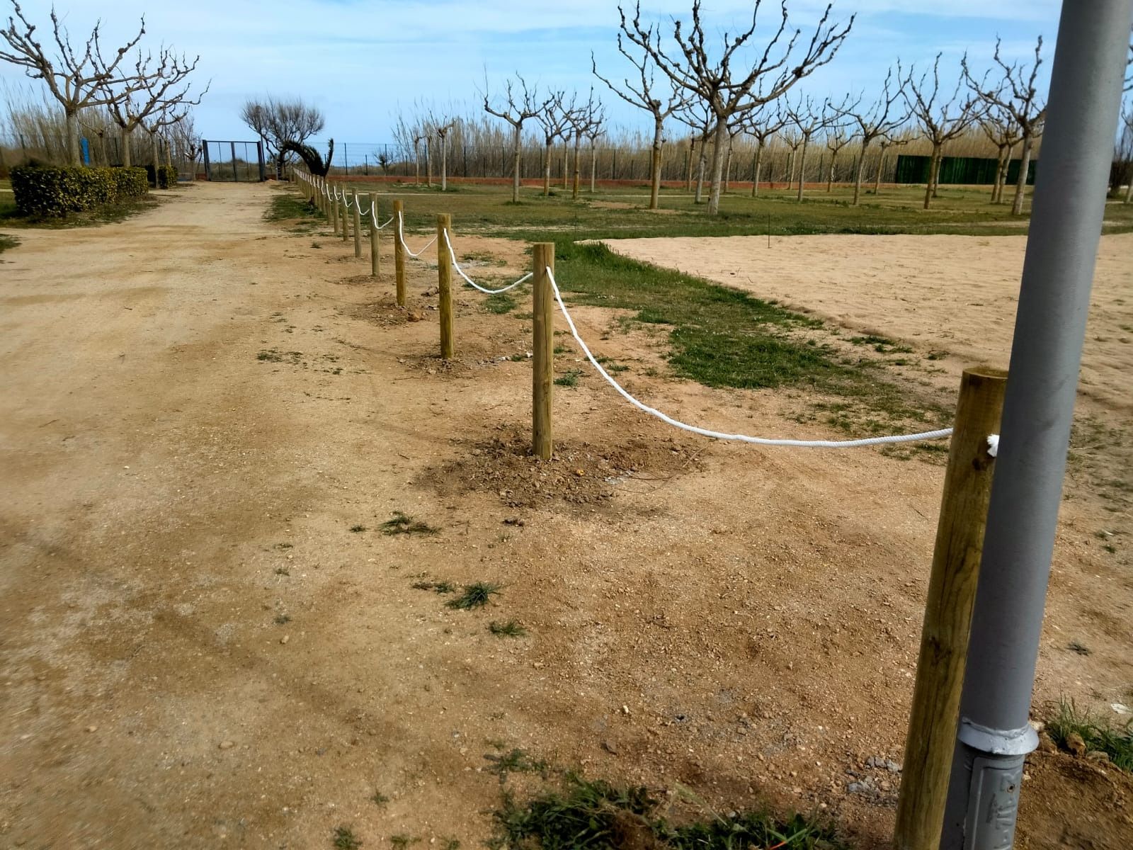 Una hilera de postes de madera con una cuerda blanca entre ellos.