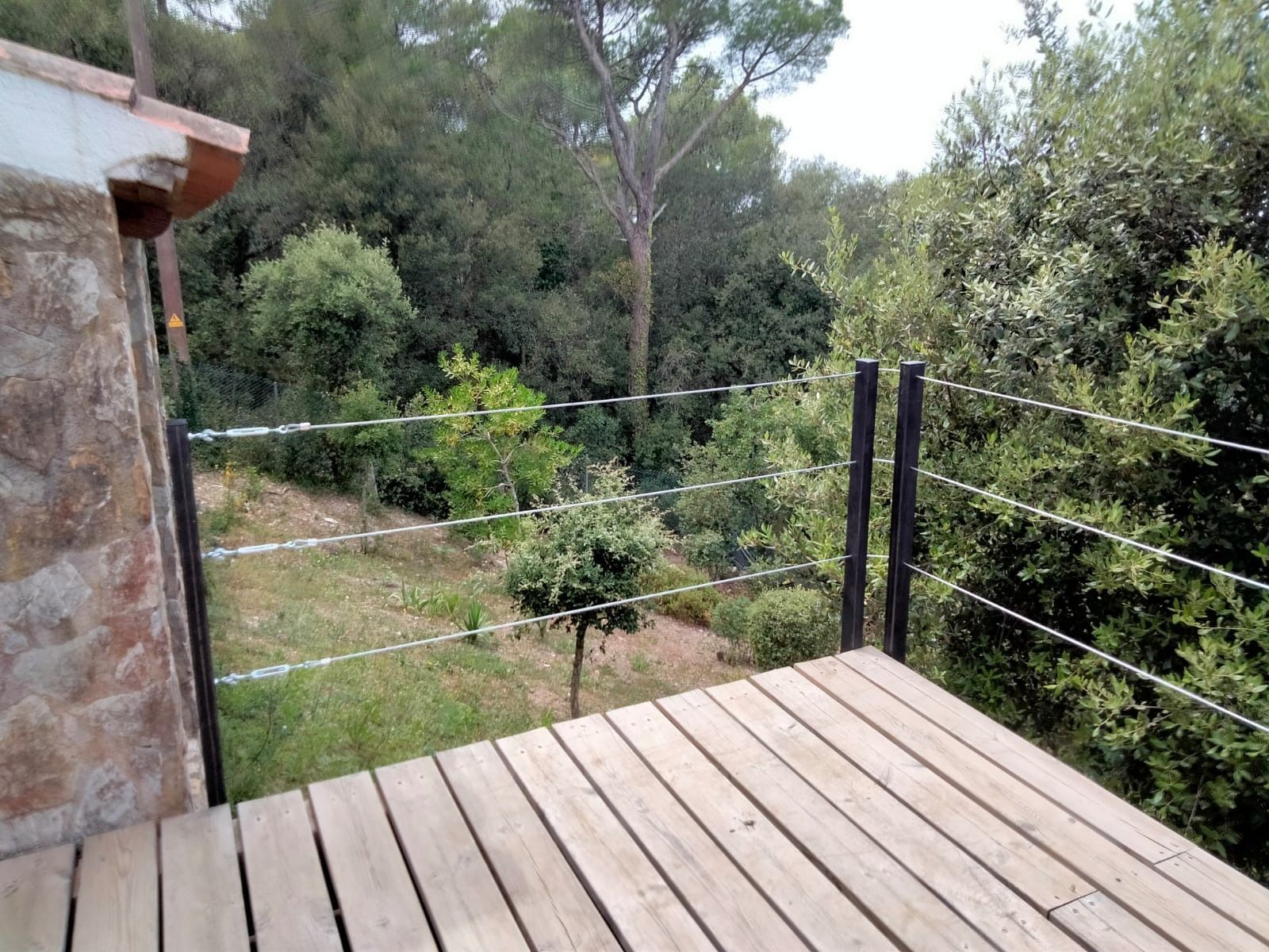 Una terraza de madera con una valla y árboles al fondo.
