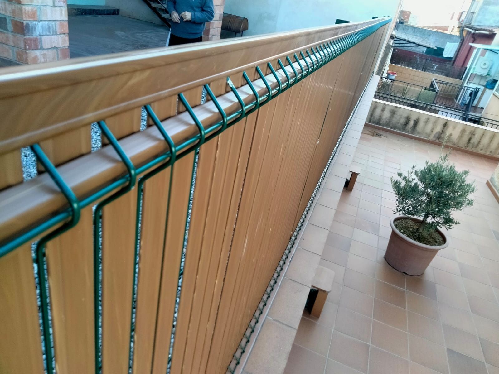 Un balcón con una valla de madera y una planta en maceta.