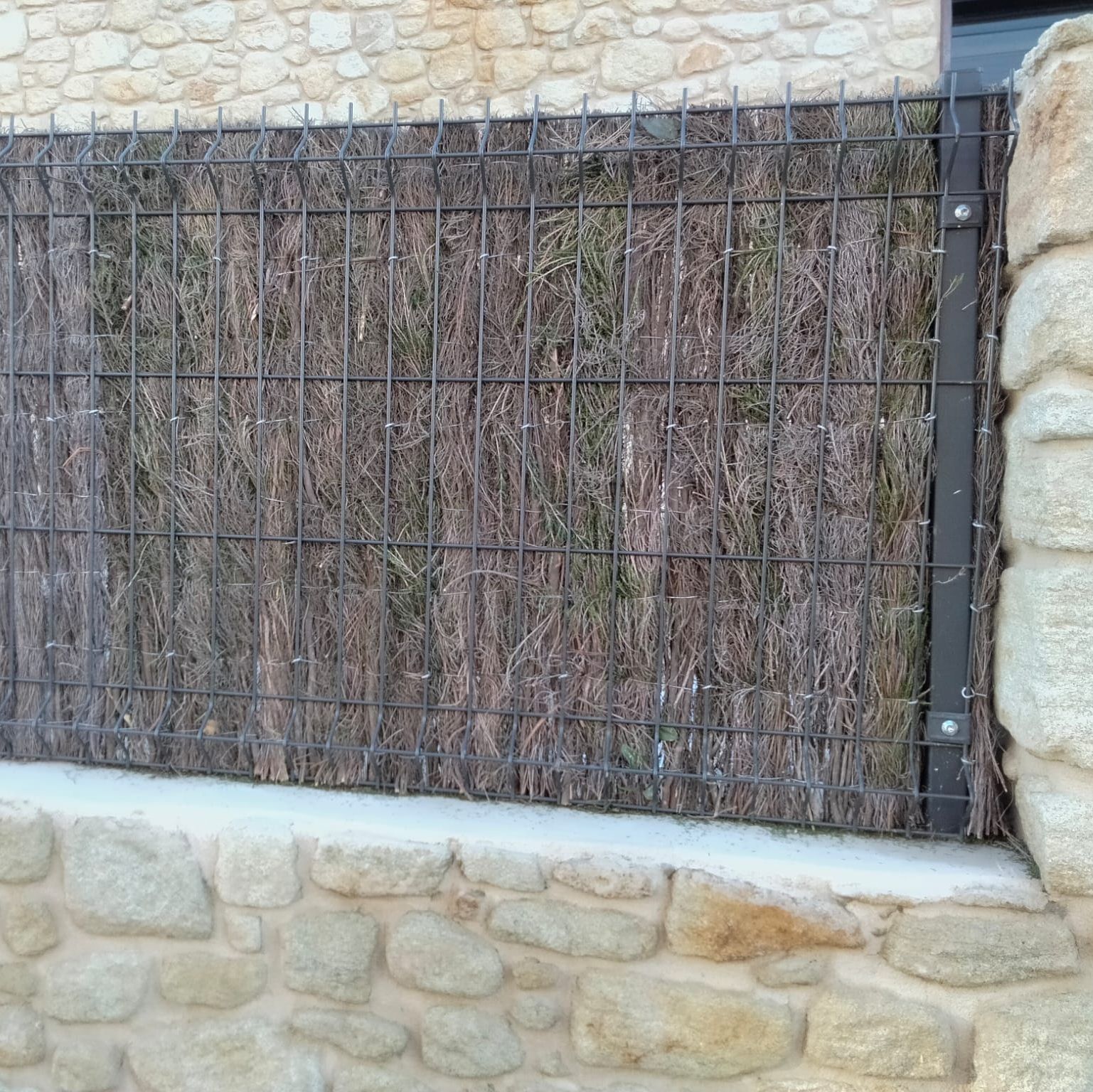 Un muro de piedra con una valla delante