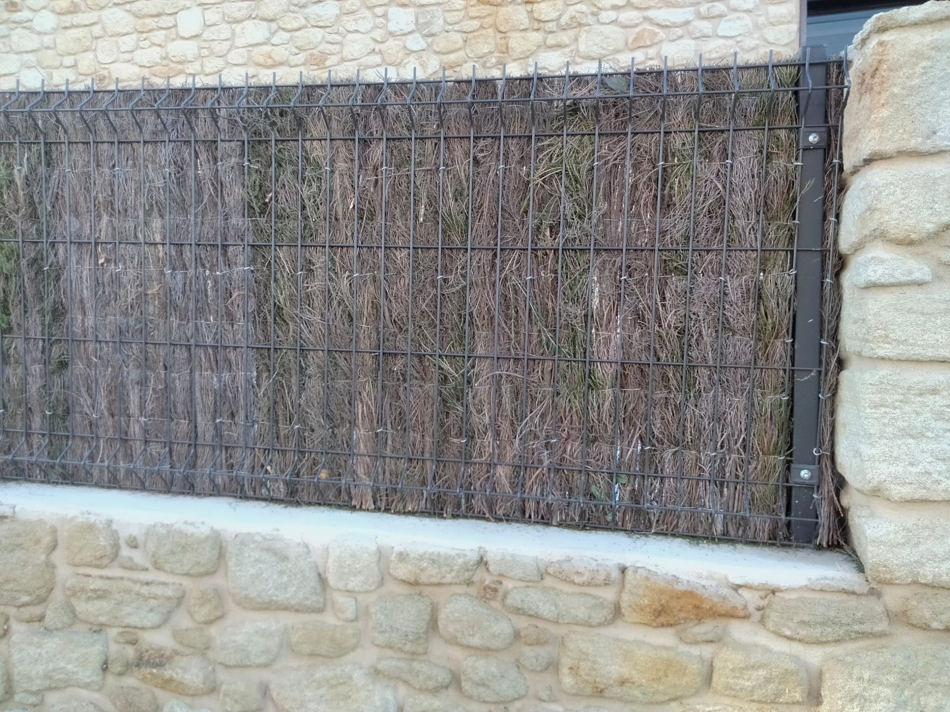 Un muro de piedra con una valla delante