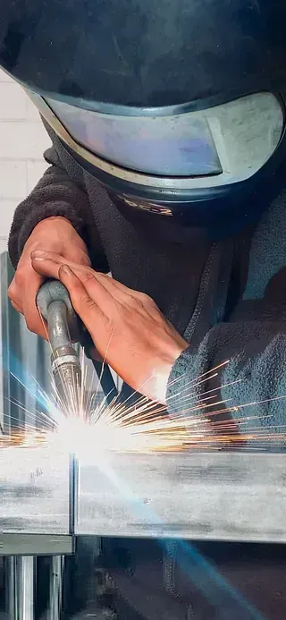 Un hombre que lleva un casco de soldador está soldando una pieza de metal.