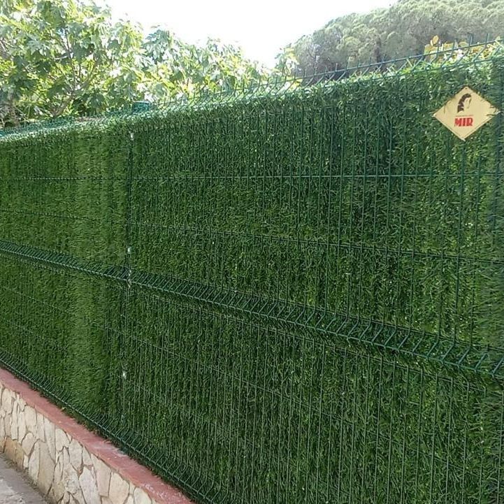 Una valla de césped artificial está rodeada por un muro de piedra.