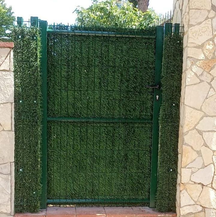 Una puerta verde está rodeada por un seto verde.