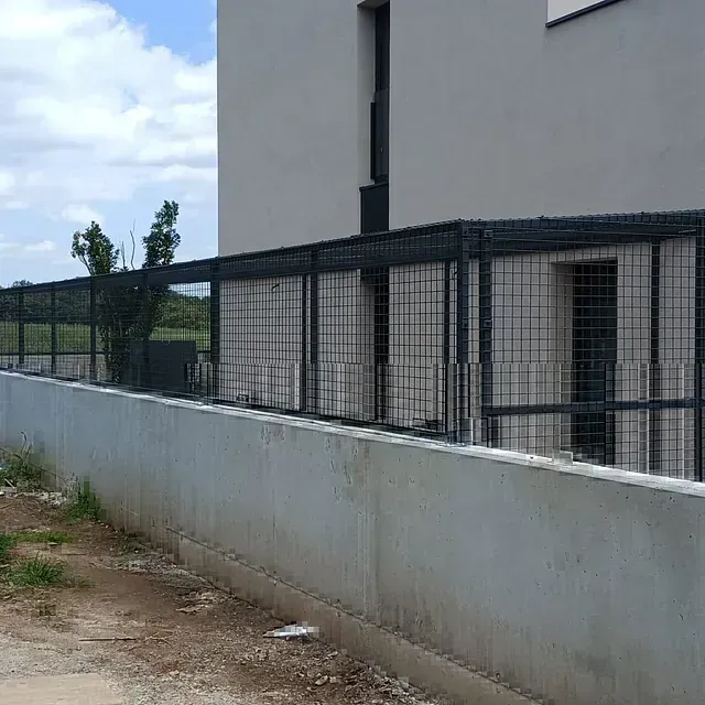 Una valla rodea un muro de hormigón al lado de un edificio.