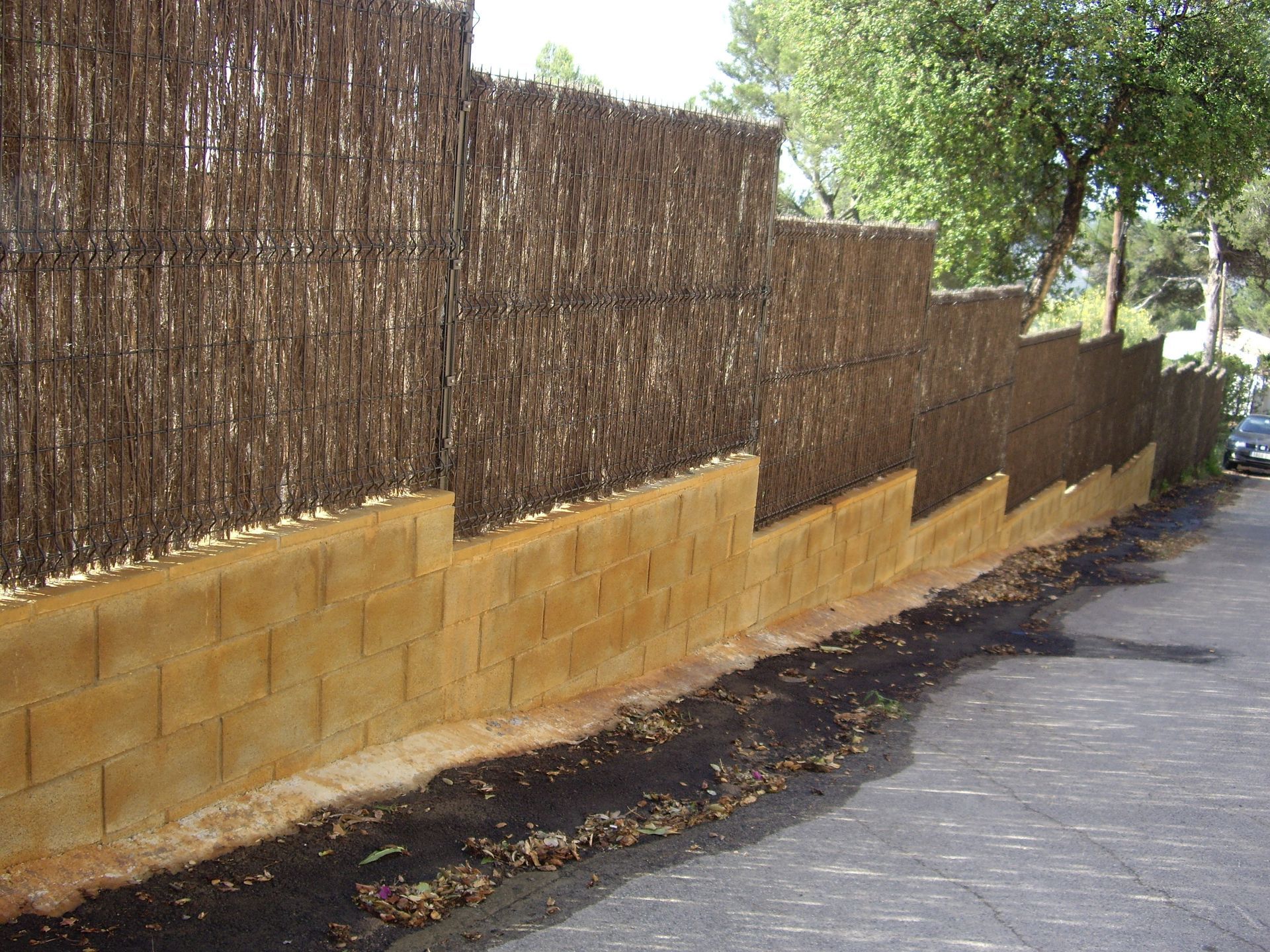 Una pared de ladrillos con una valla al fondo