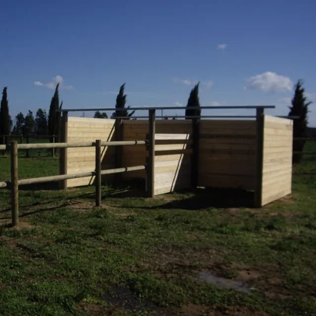 Una valla de madera rodea un pequeño edificio en un campo de hierba.