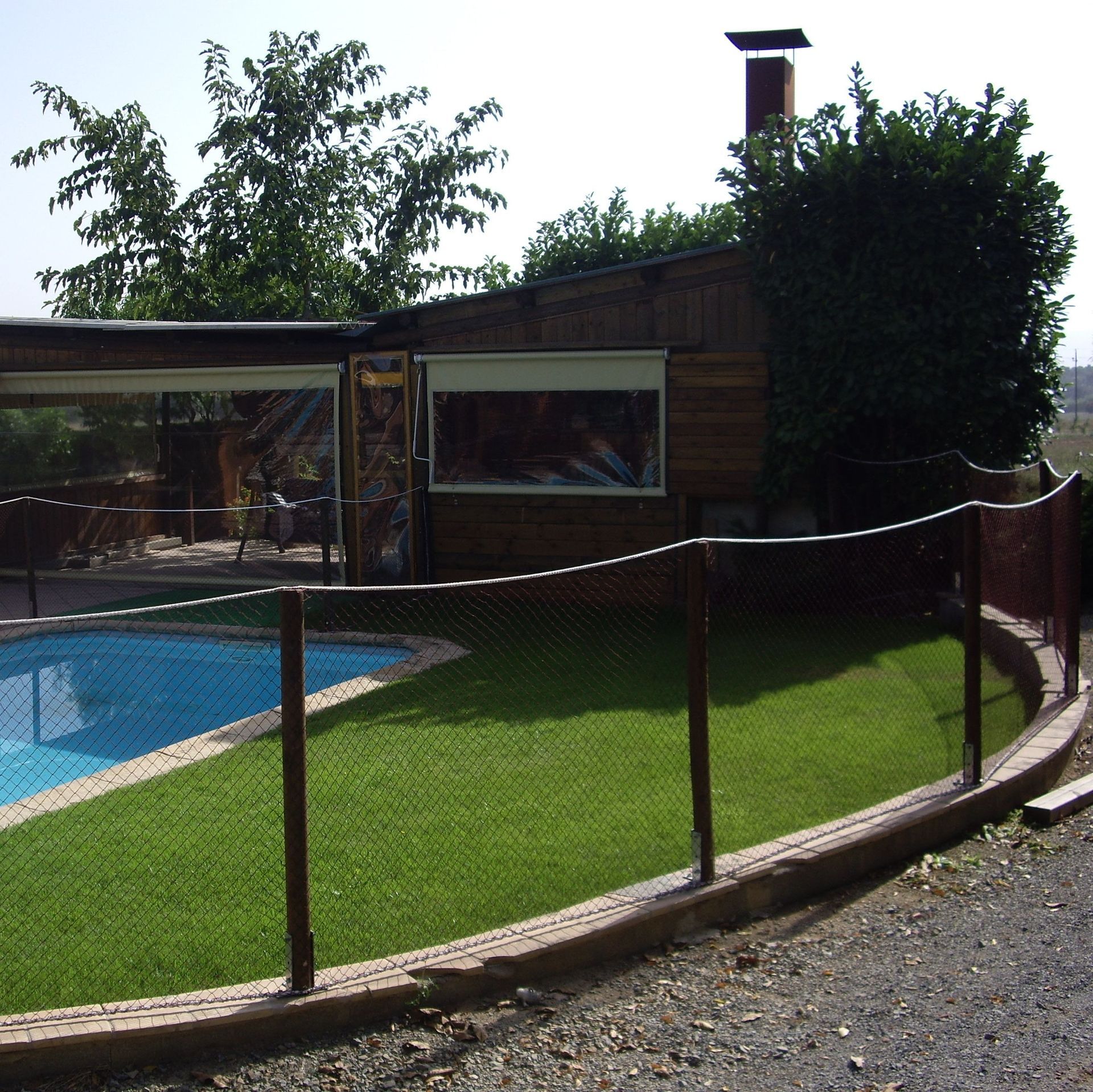 Una valla rodea una piscina delante de una casa.