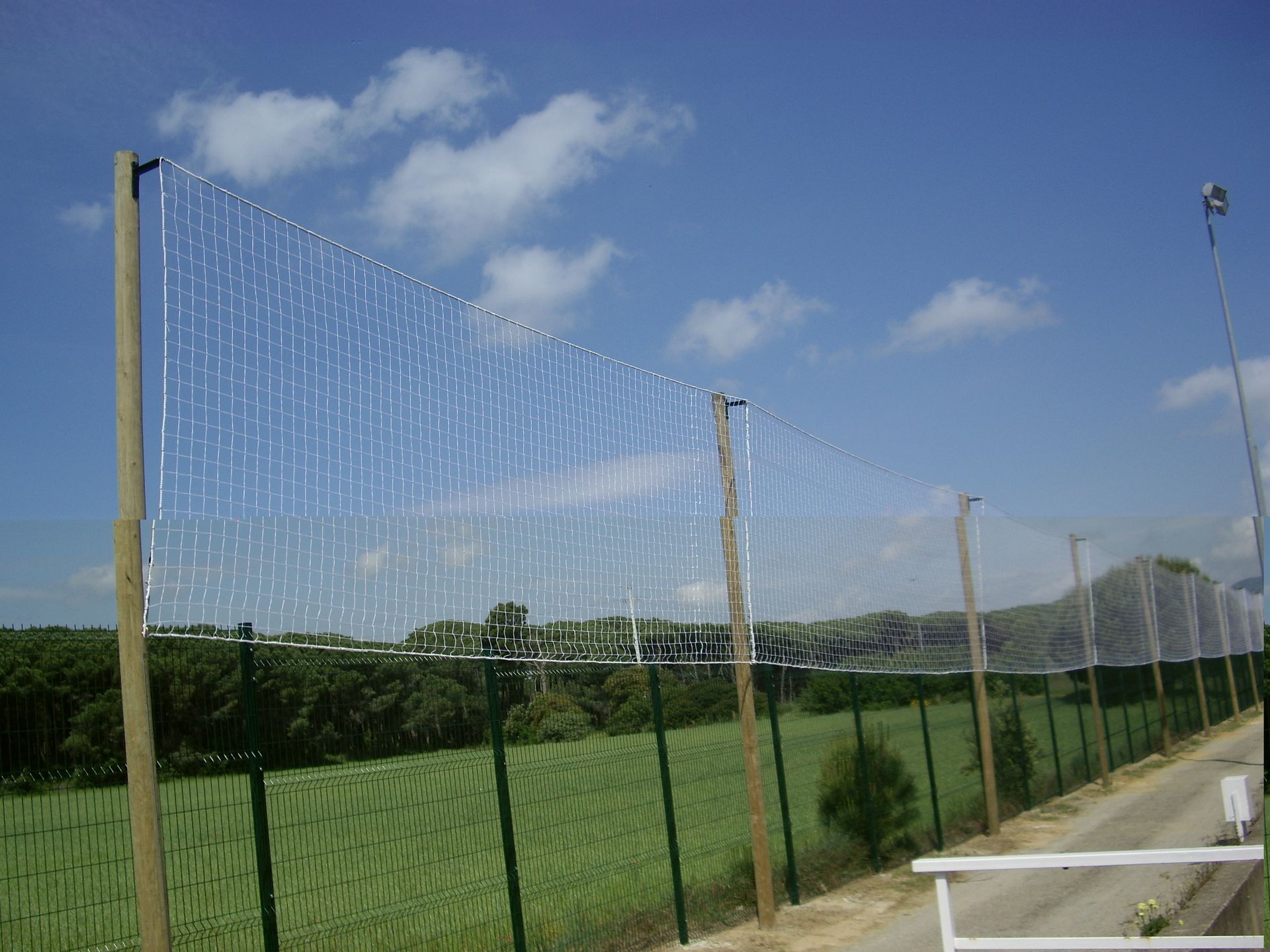 Una valla rodea un campo con un cielo azul al fondo.