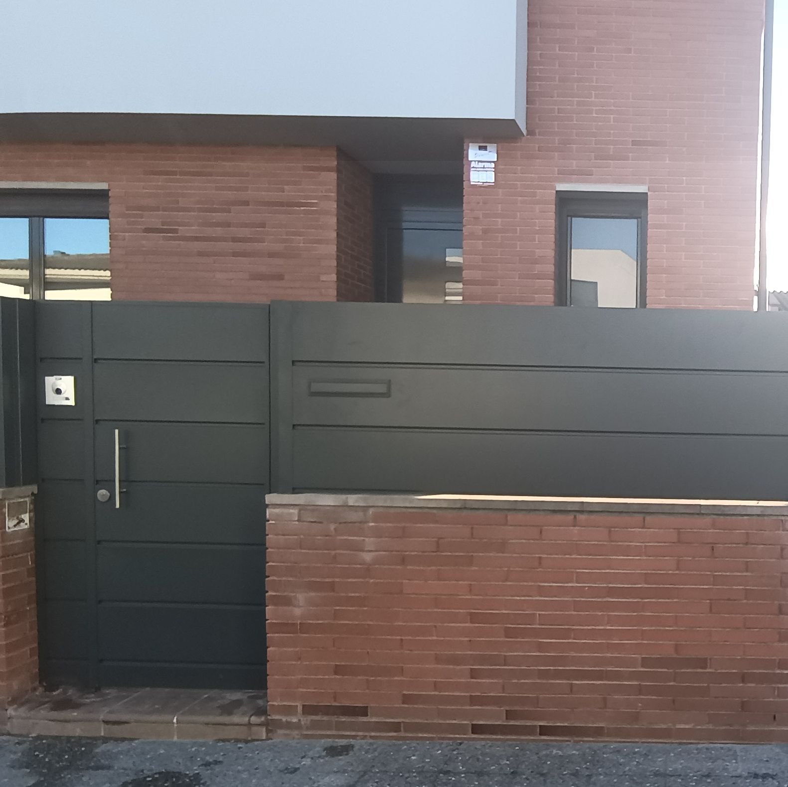 Un edificio de ladrillo con una valla negra delante.