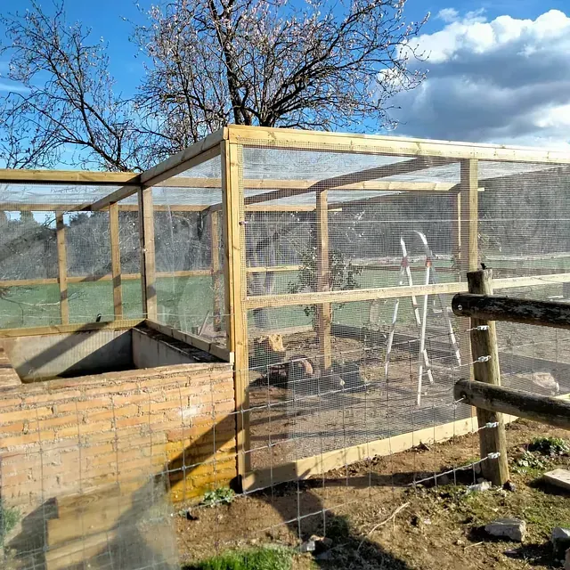Una jaula de madera con una escalera atada a ella en un campo.