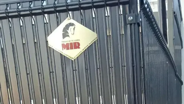 Una valla metálica con un cartel que dice mir.