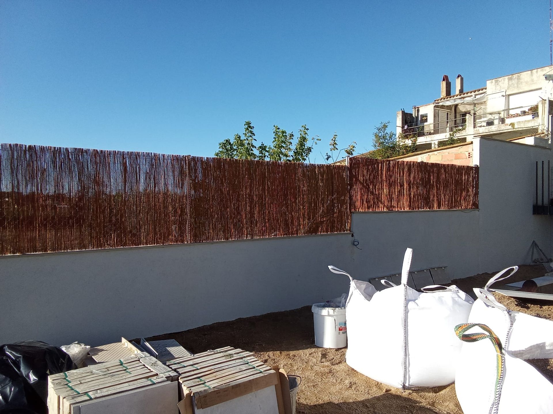 Una pared blanca con una valla marrón detrás.