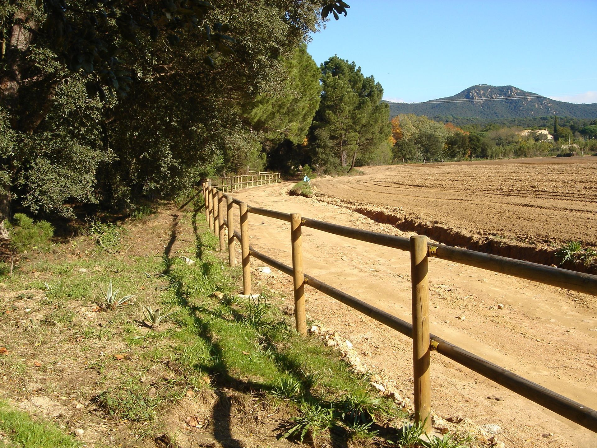 Una valla de madera al costado de un camino de tierra