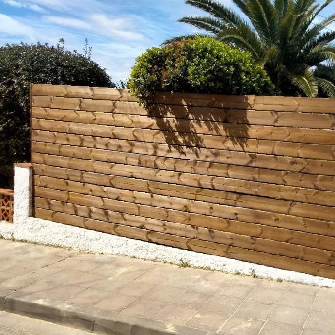 Una valla de madera con palmeras al fondo.