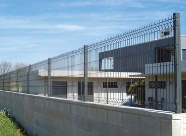 Una valla rodea un edificio con una pared de ladrillos.