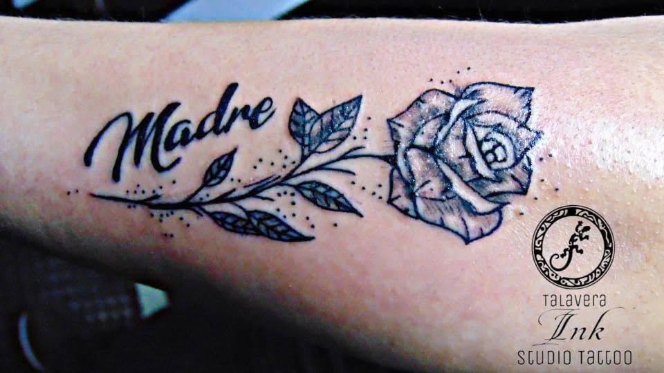 Tatuaje de «Madre» con una rosa y enredaderas con hojas en tinta negra sobre la piel