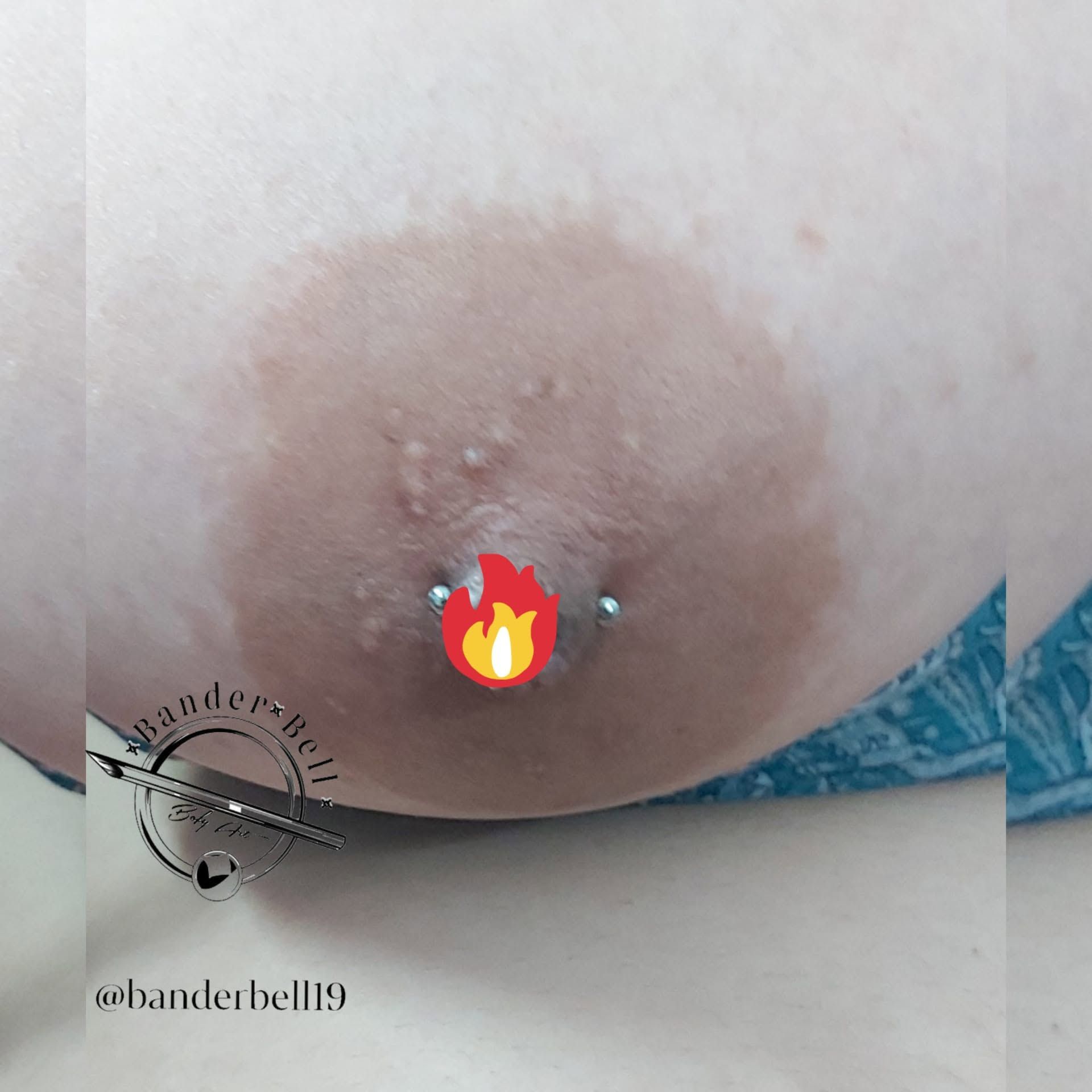 Primer plano de un pecho con la areola y el pezón bien visibles, parcialmente cubiertos por un emoji de llama
