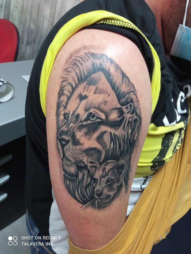 Tatuaje en la parte superior del brazo de un león rugiendo, con una camiseta sin mangas amarilla y negra a la vista