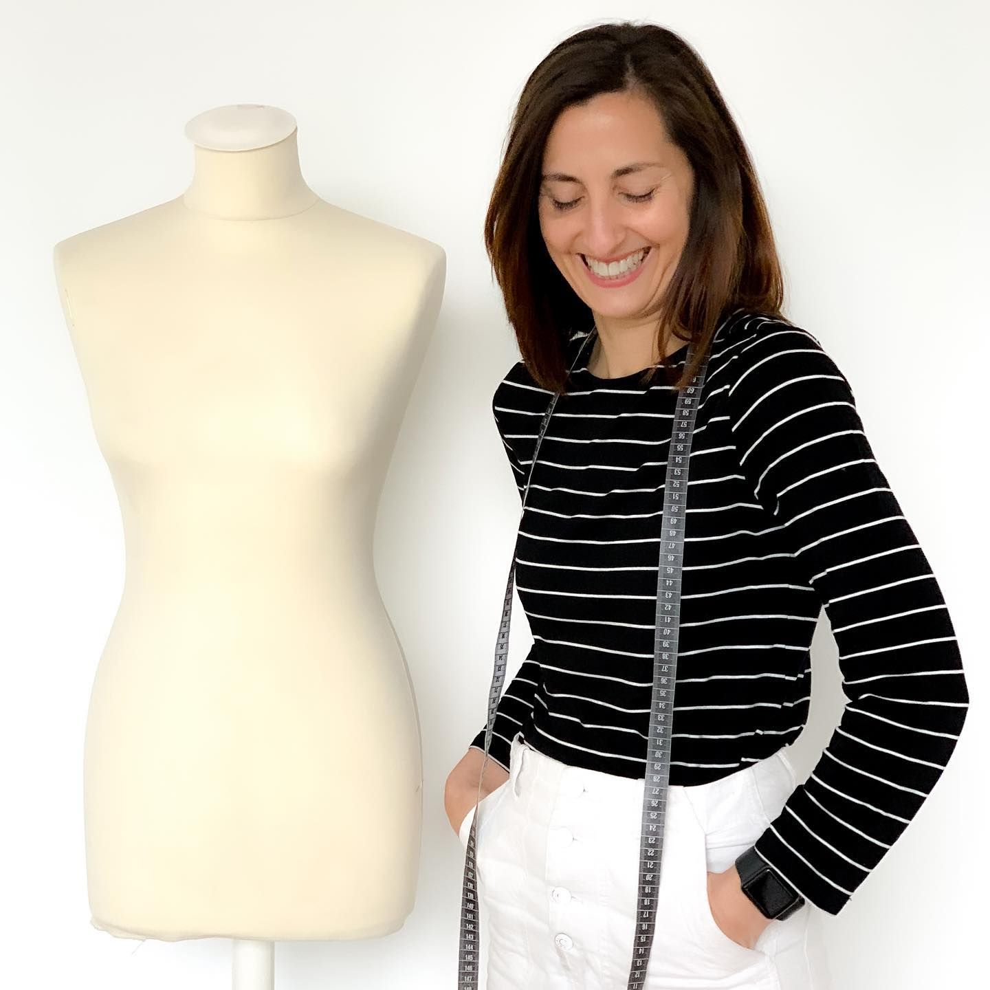 Una mujer con una camisa de rayas blancas y negras está de pie junto a un maniquí.