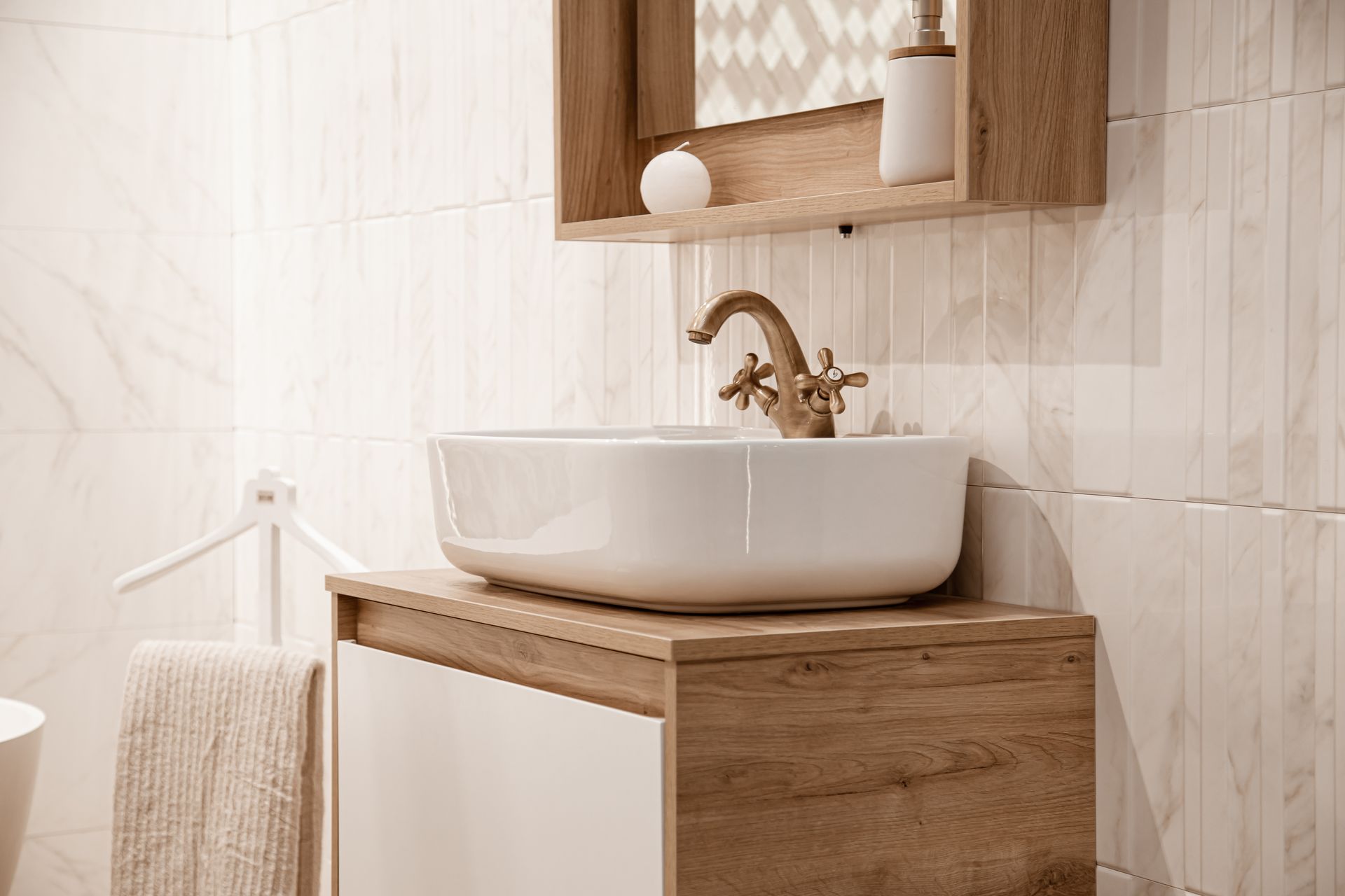 Meuble lavabo moderne avec vasque blanche, armoire en bois et mur carrelé avec étagère.
