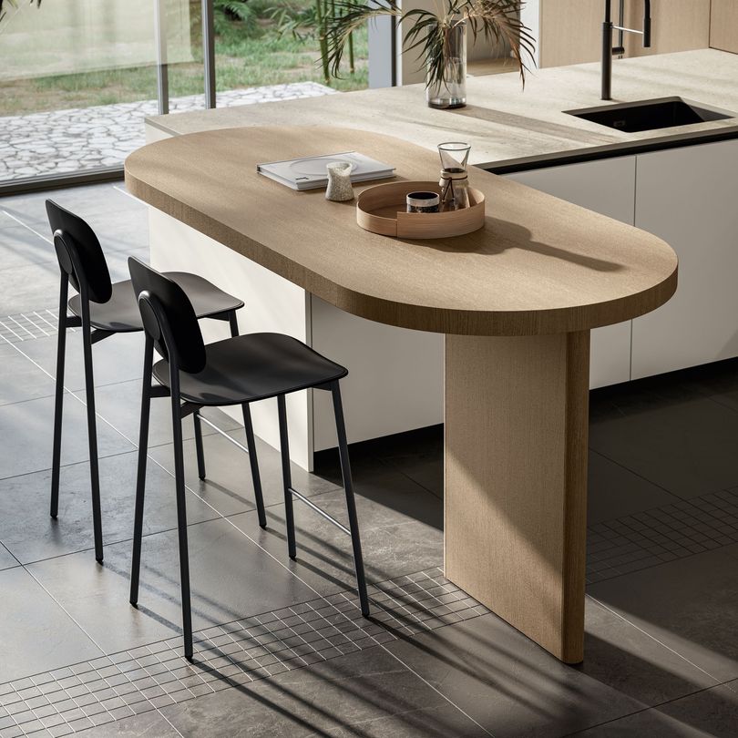 Cuisine moderne avec placards en bois chaleureux, électroménager en inox et lumière naturelle grâce à une fenêtre.