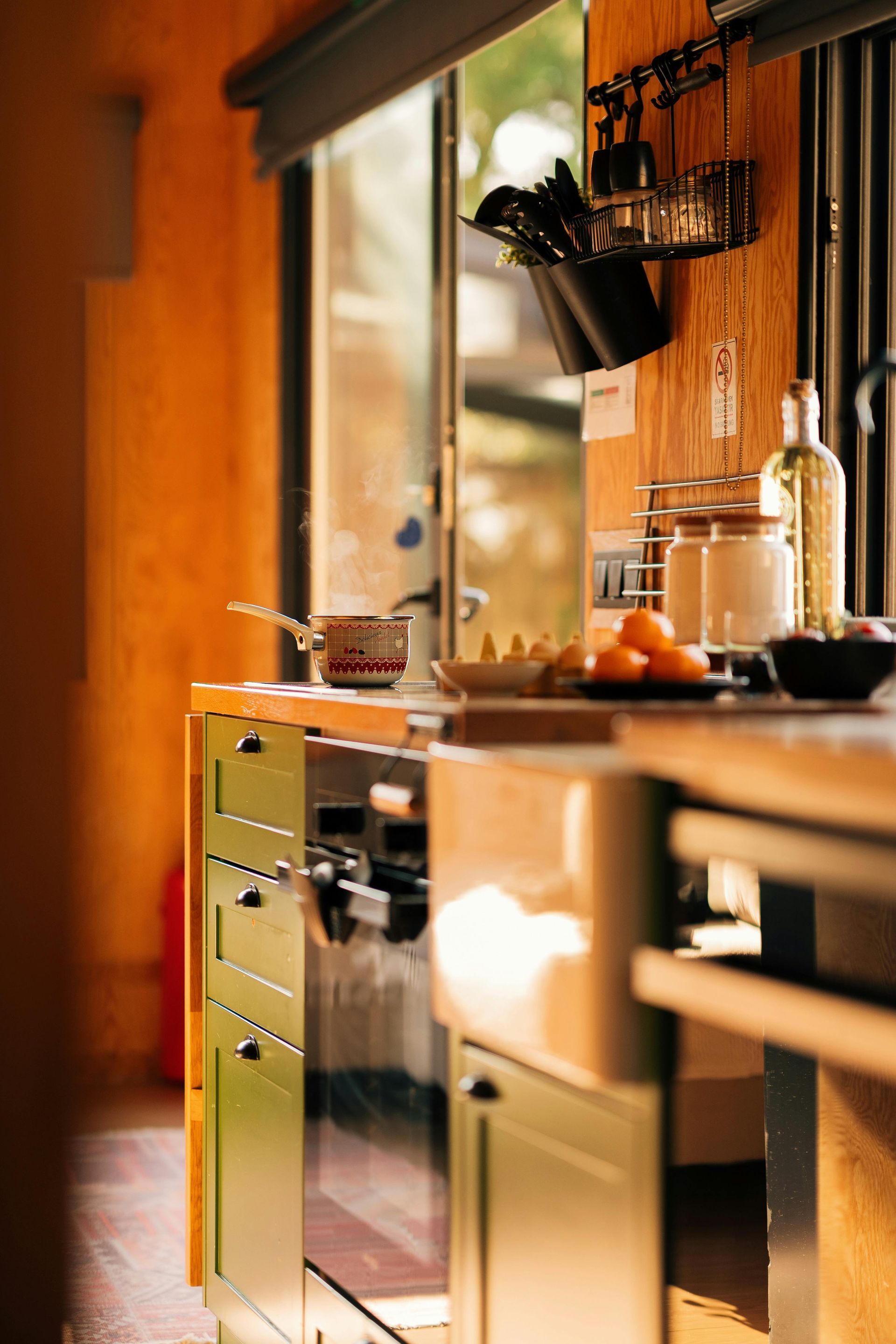 Cuisine moderne avec placards en bois chaleureux, électroménager en inox et lumière naturelle grâce à une fenêtre.