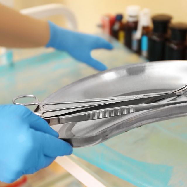 Una persona que lleva guantes azules sostiene un par de tijeras.