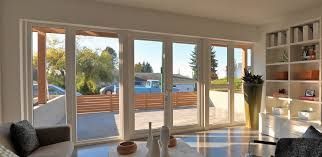 El luminoso salón cuenta con grandes puertas de cristal que dan a un patio, una estantería blanca y cómodos asientos.