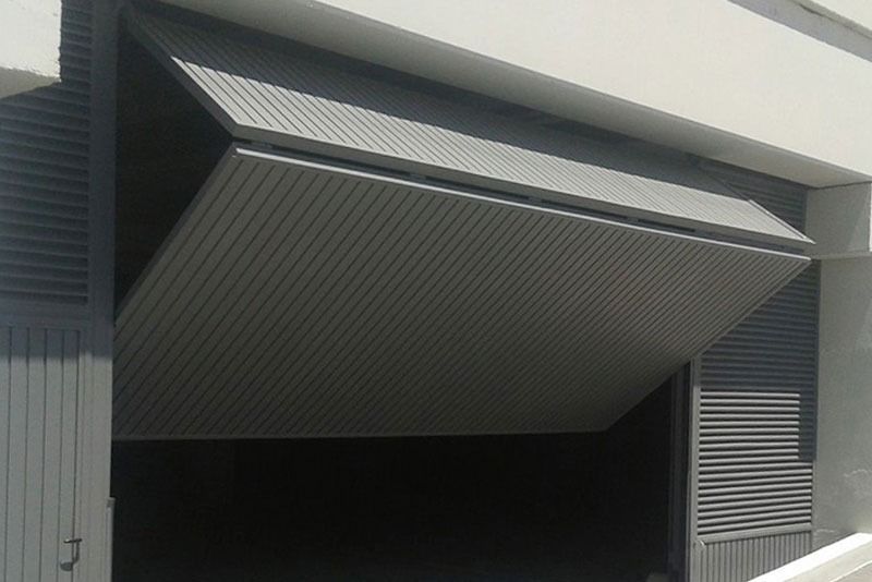 Una puerta de garaje está abierta con un techo gris.