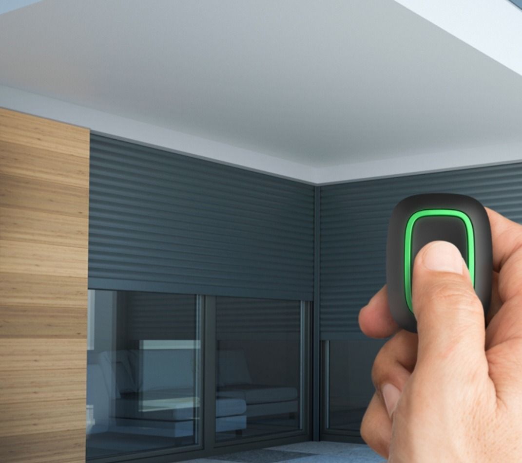 Una persona sostiene un control remoto con una luz verde.