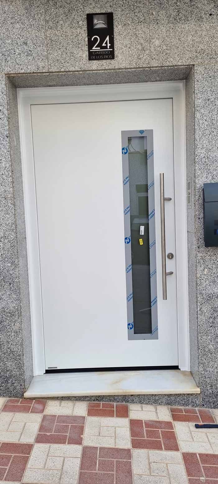 Puerta blanca con ventana y tirador plateado, número 24 arriba.