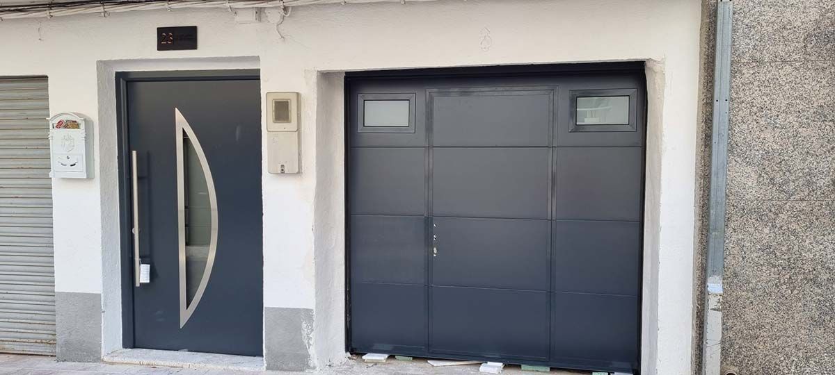 Exterior de un edificio con una puerta gris oscuro y una puerta de garaje.
