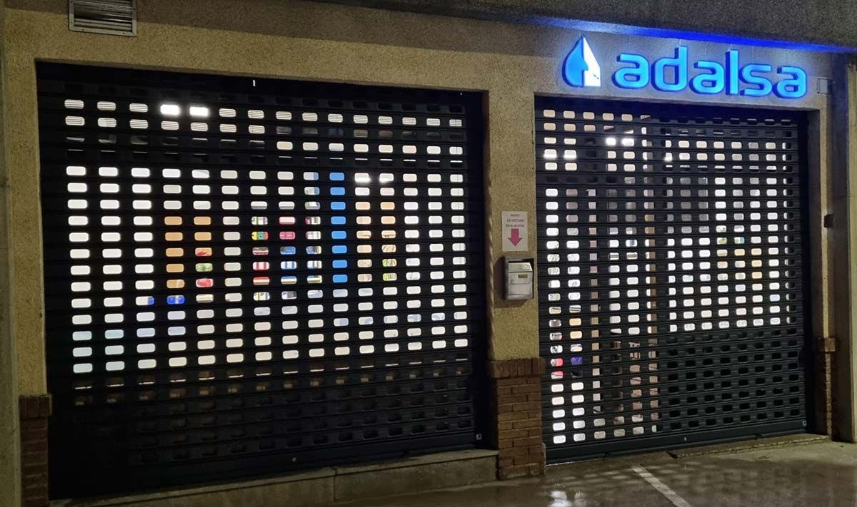 Tienda cerrada con puertas metálicas enrollables y cartel azul