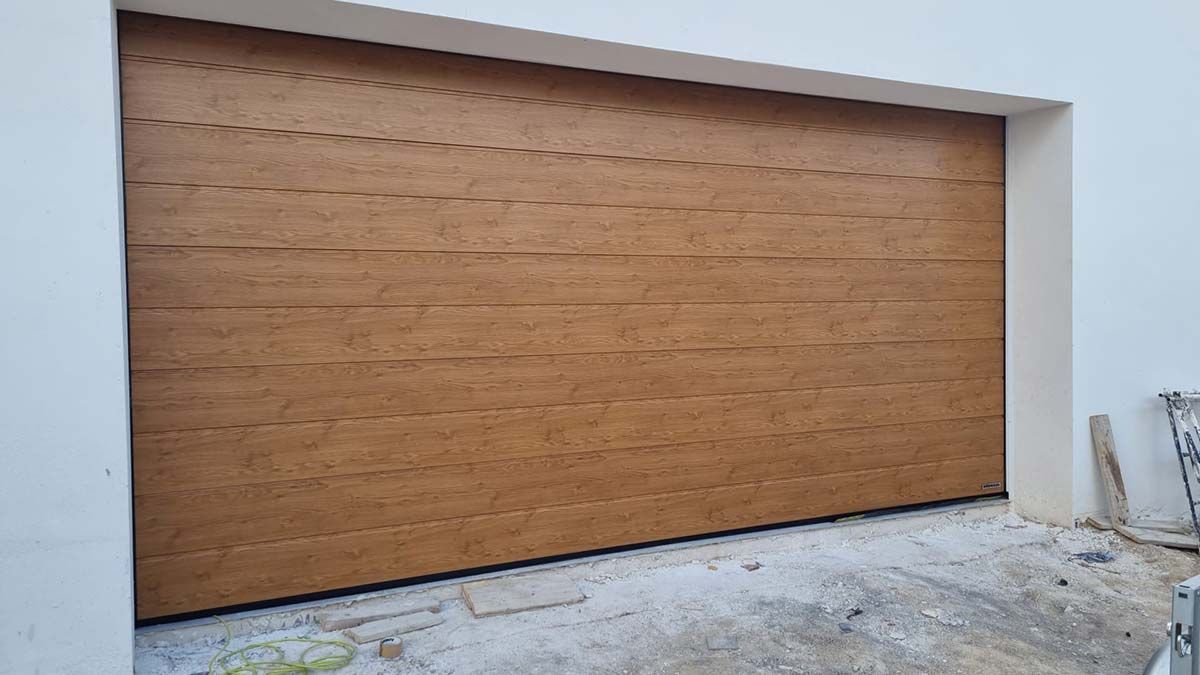 Puerta de garaje de madera marrón en un edificio blanco.