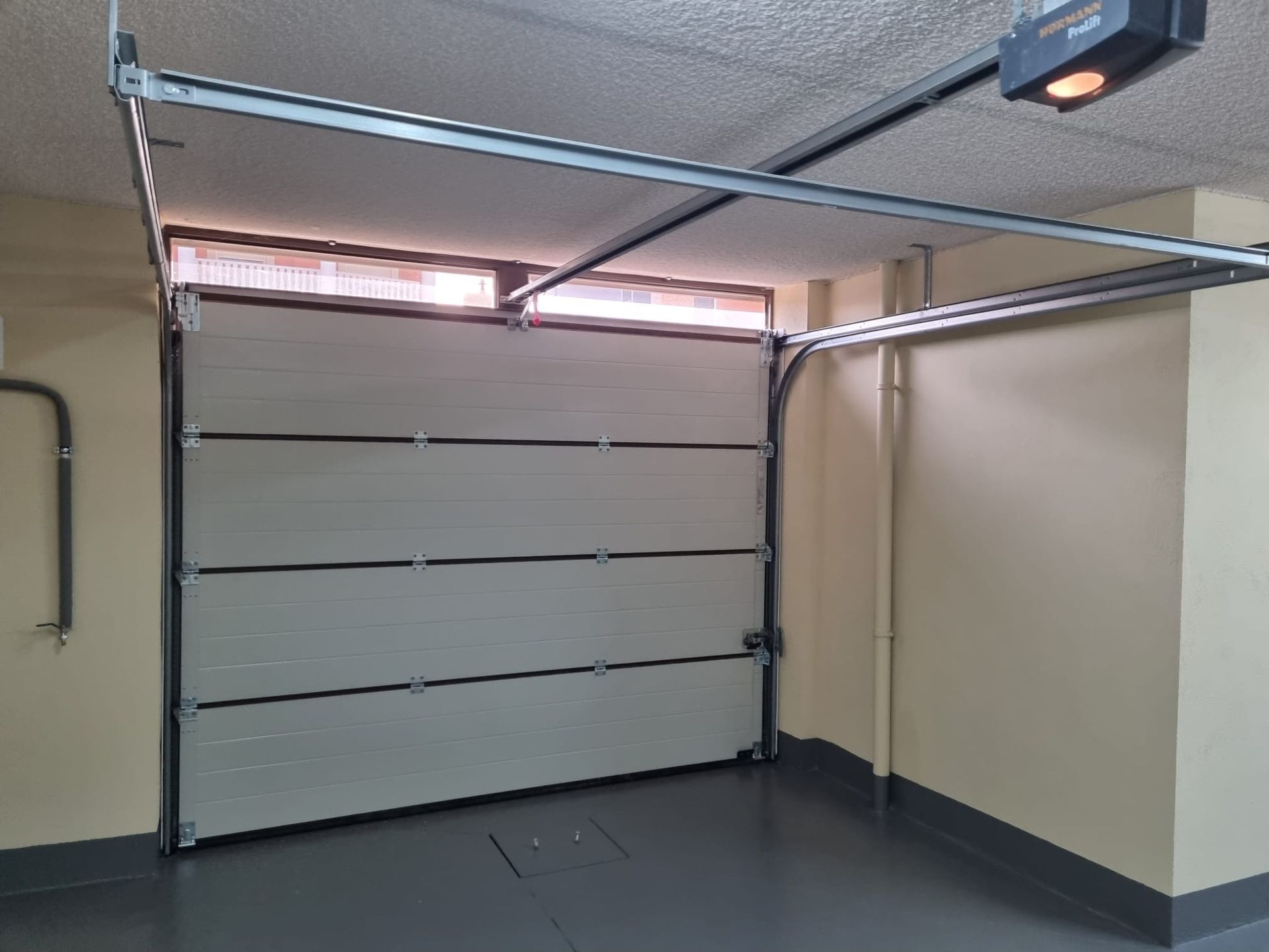 Un garaje vacío con una puerta de garaje abierta y una ventana.