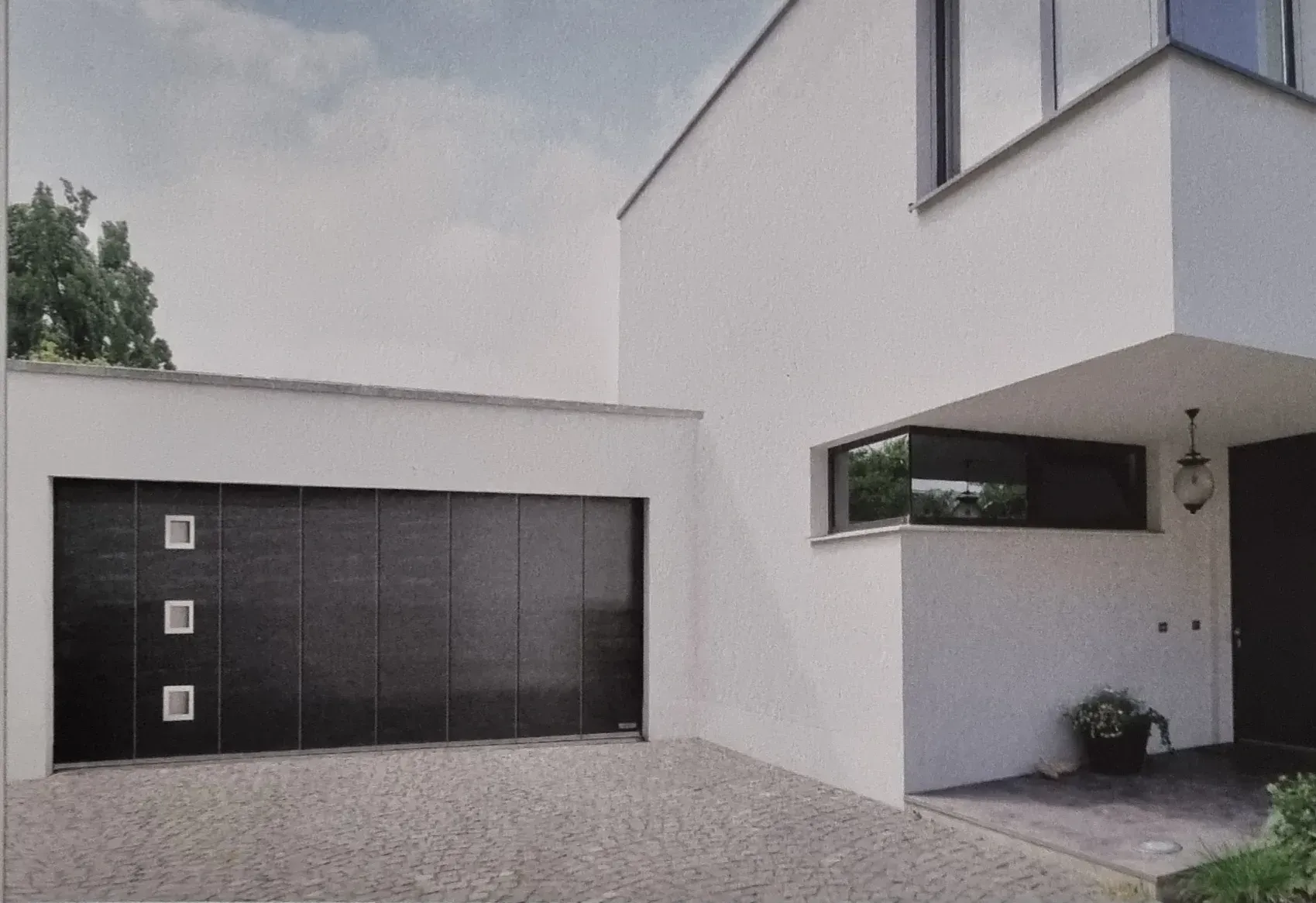 Una casa blanca moderna con una puerta de garaje negra.