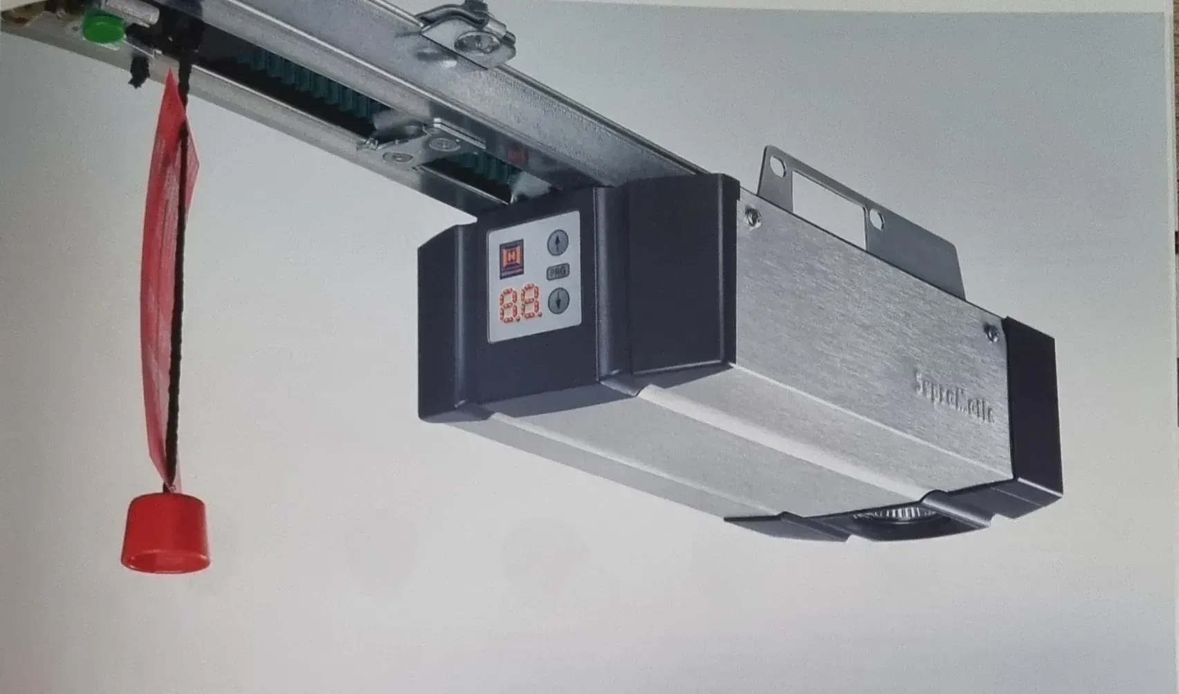 Una imagen de un abridor de puerta de garaje con un botón rojo colgando de él.