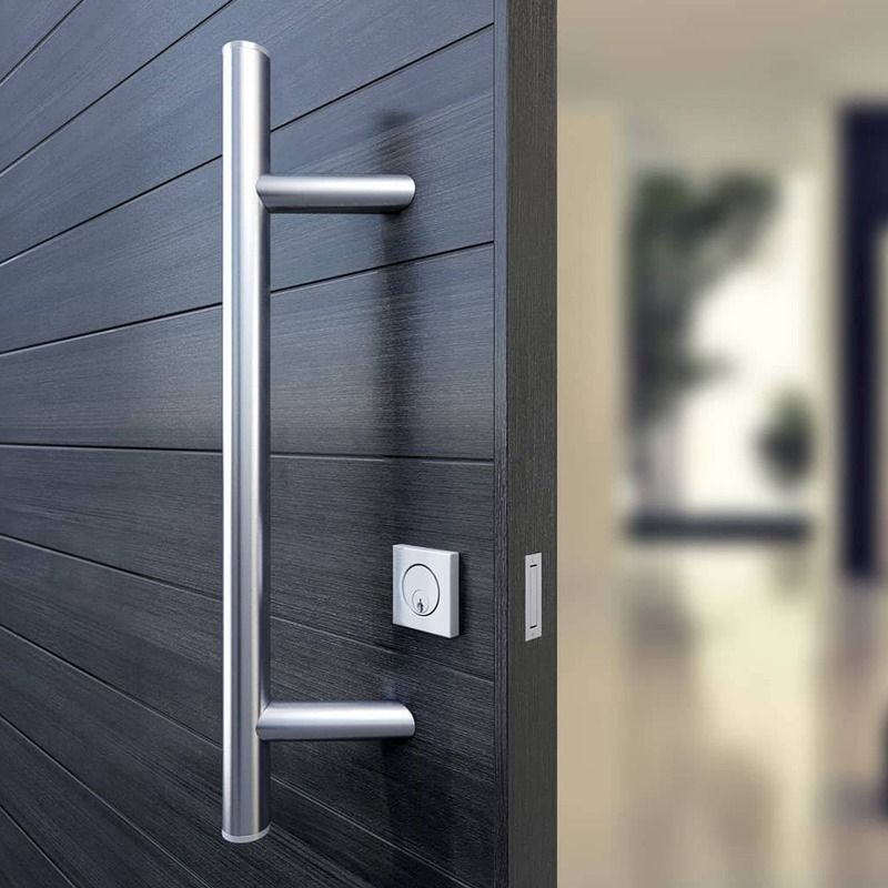 Una manija de puerta de acero inoxidable está colgada en una puerta de madera.