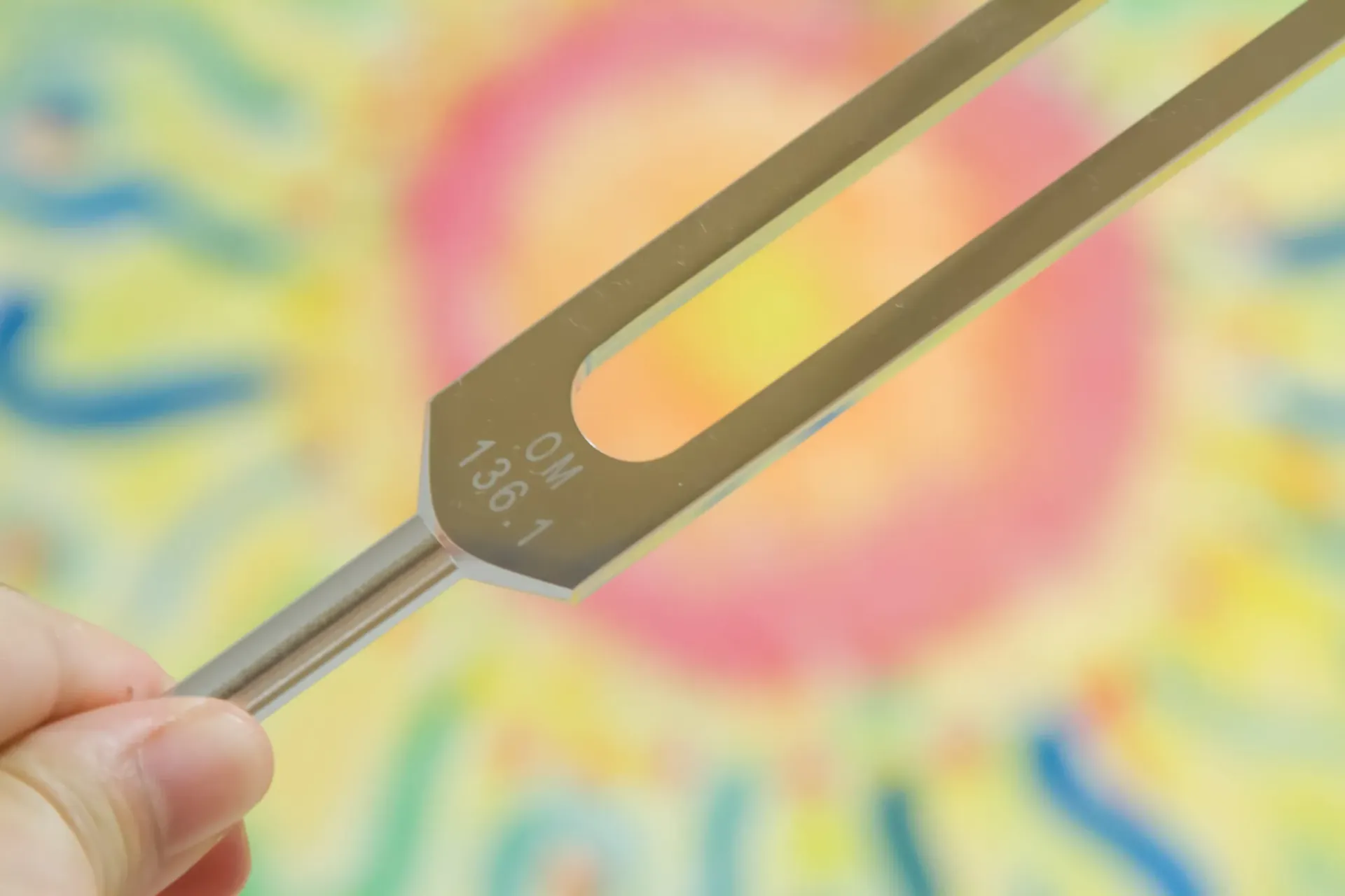 Una mano sostiene un diapasón de metal con la inscripción 