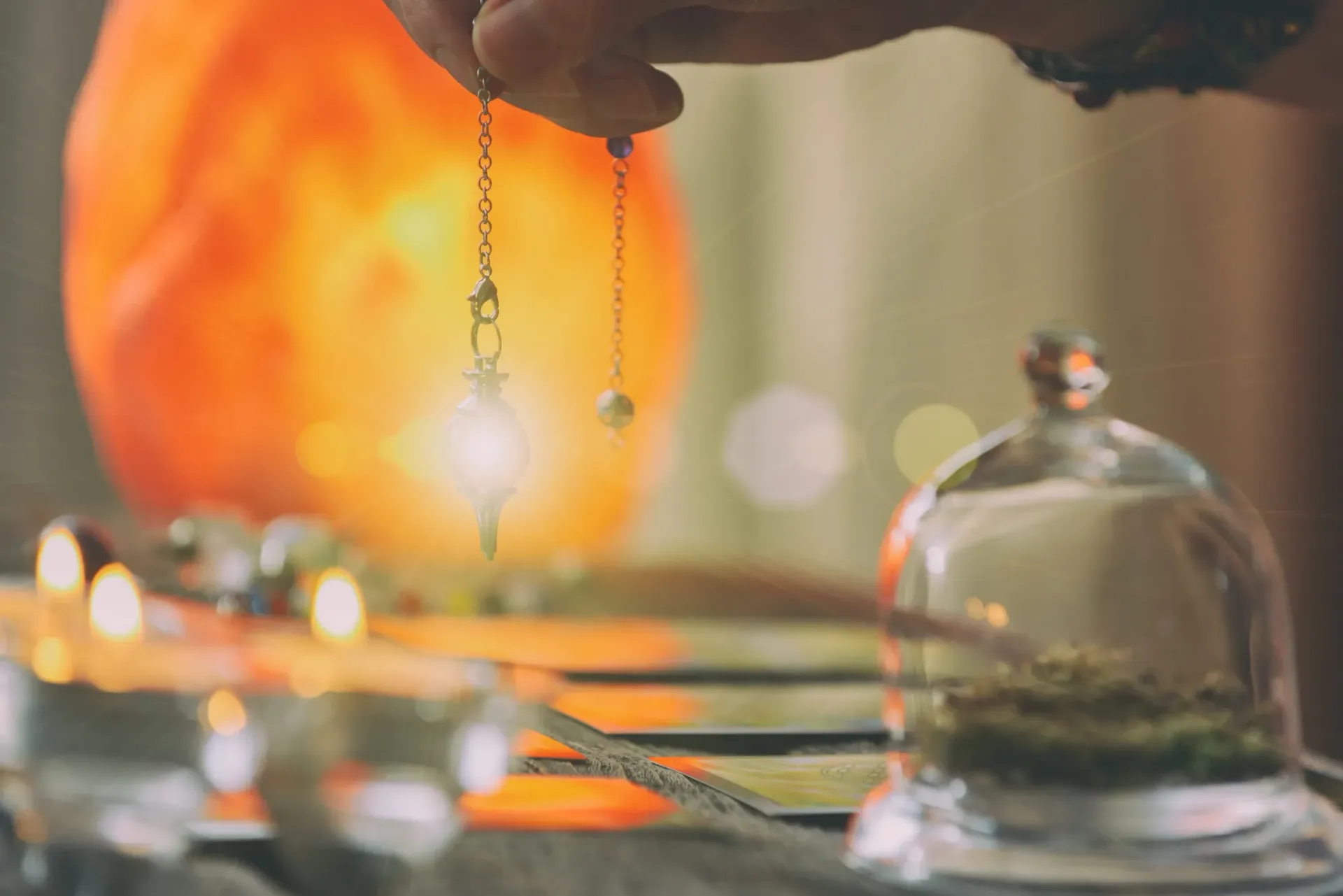 Una mano sostiene un péndulo de cristal