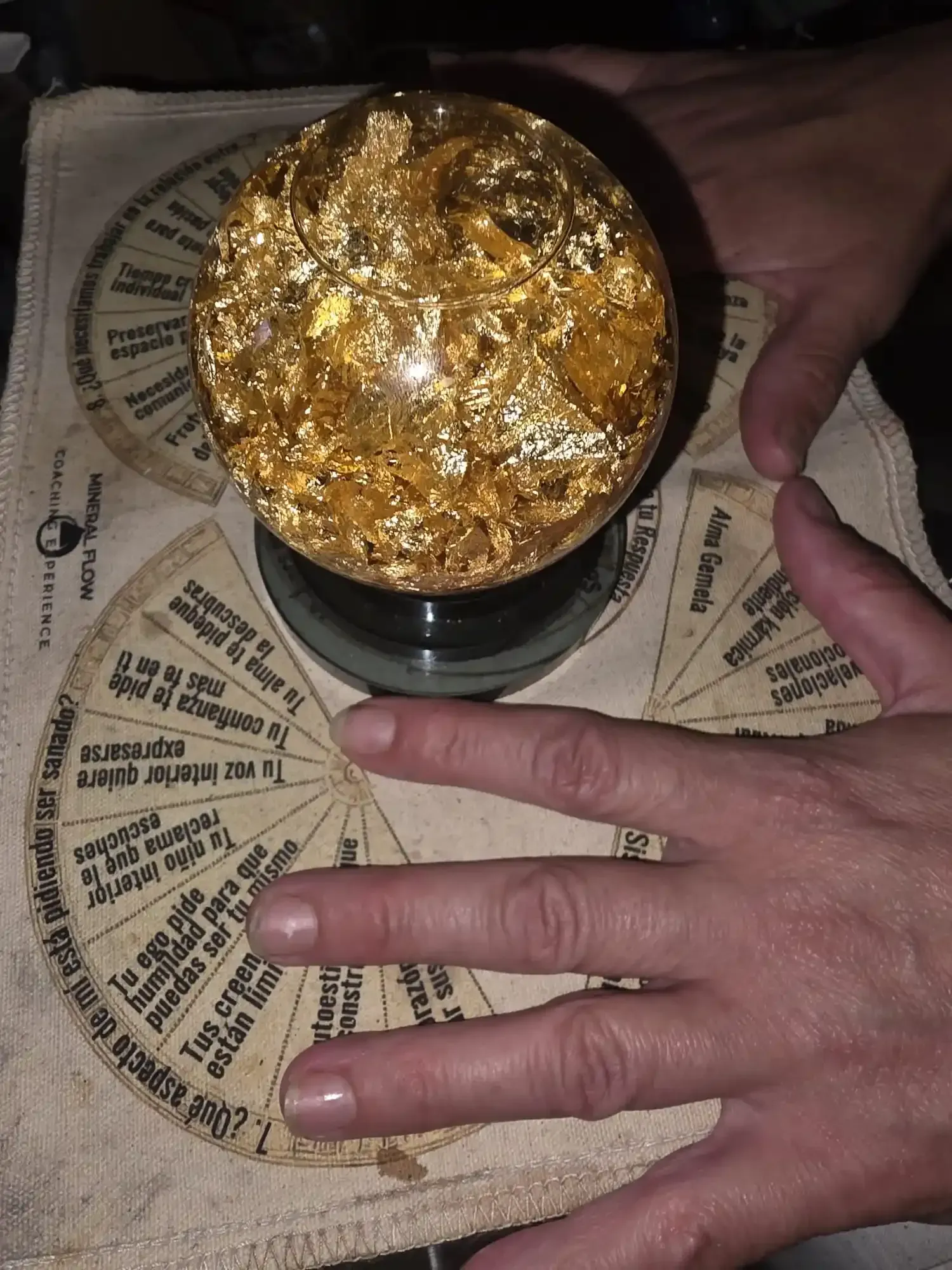 Unas manos se ciernen sobre una esfera salpicada de oro