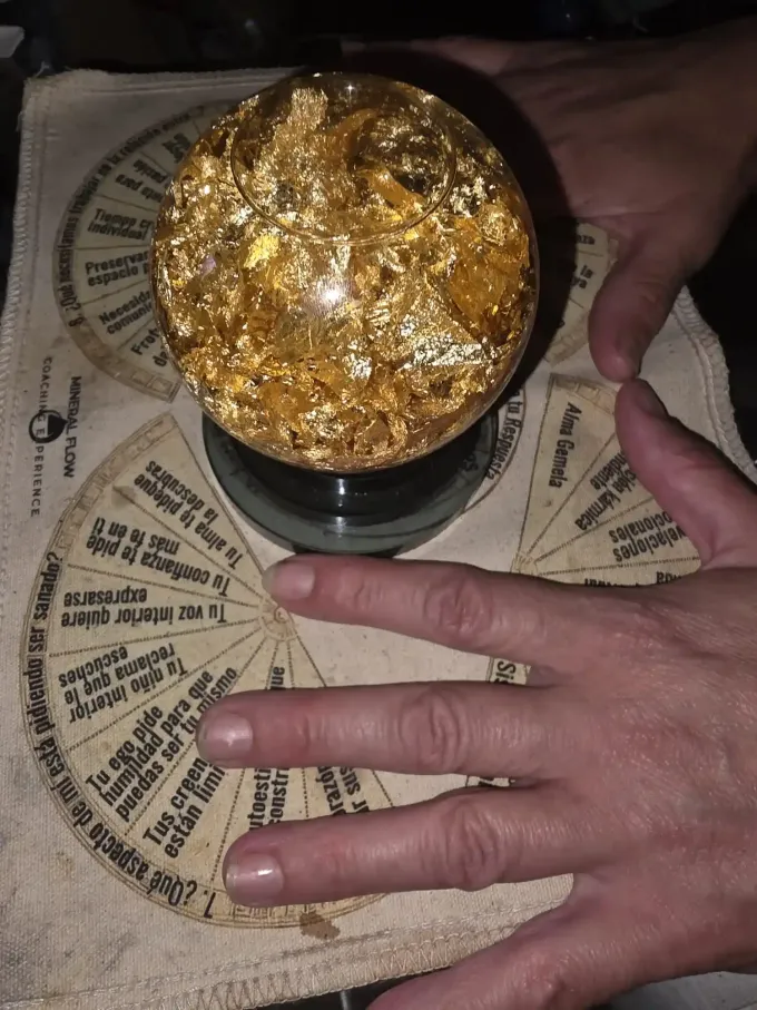 Unas manos se ciernen sobre una esfera salpicada de oro