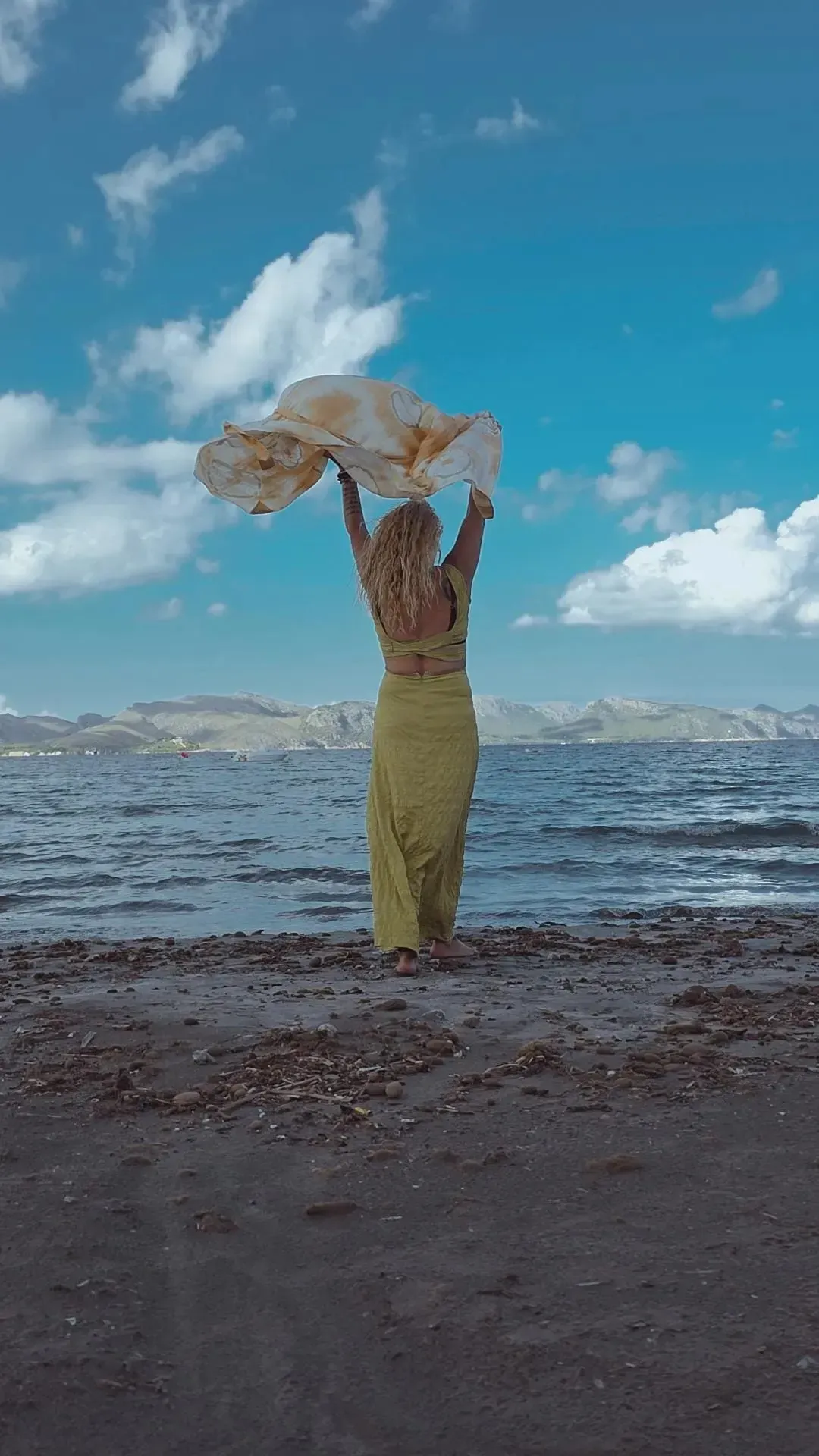 Una persona vestida de amarillo se encuentra de pie en una playa