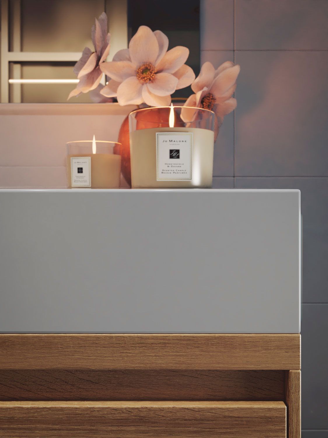 Hay dos velas en el mostrador del baño al lado de flores.