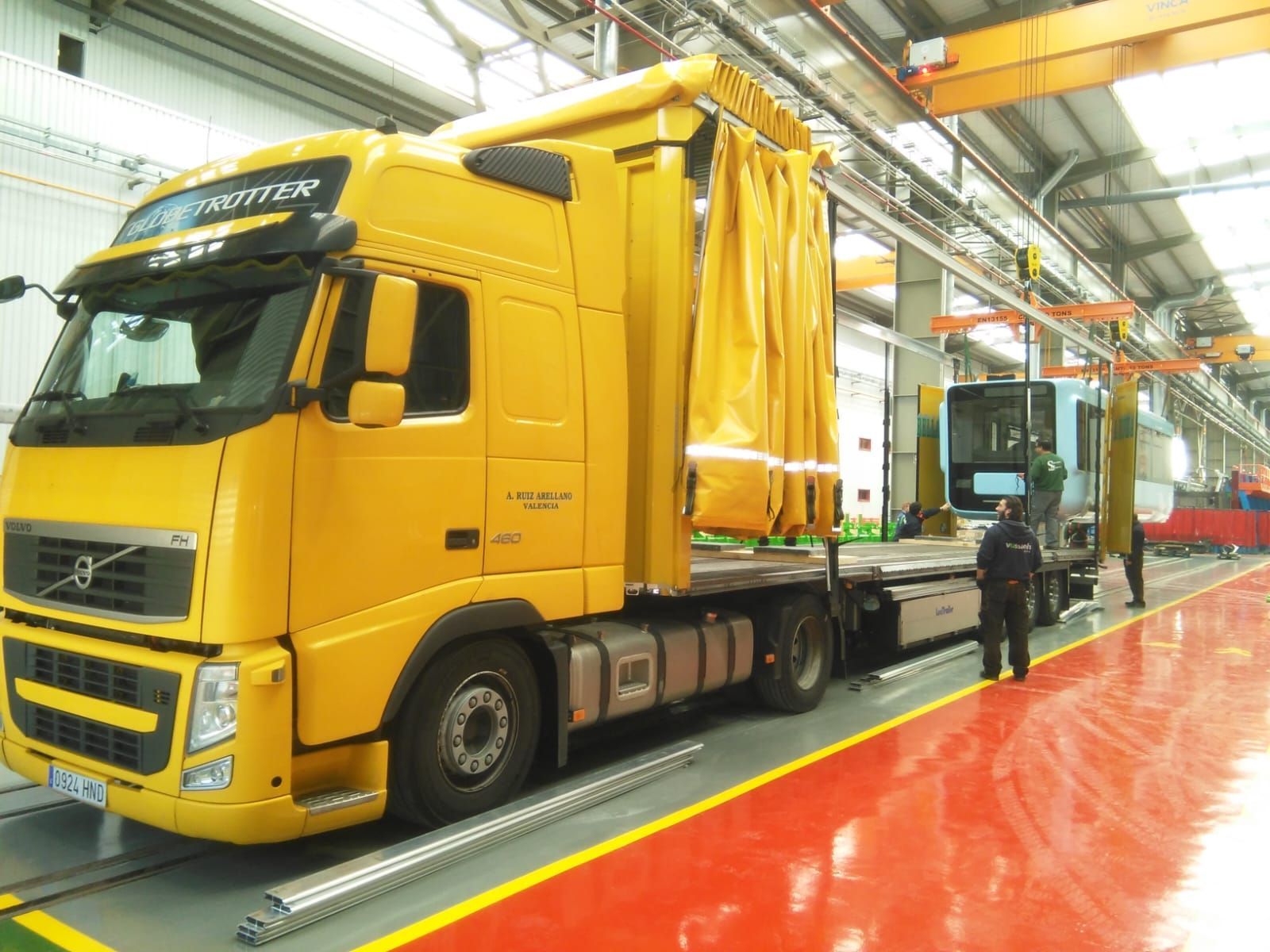 Un camión amarillo está estacionado en un almacén con un hombre parado a su lado.